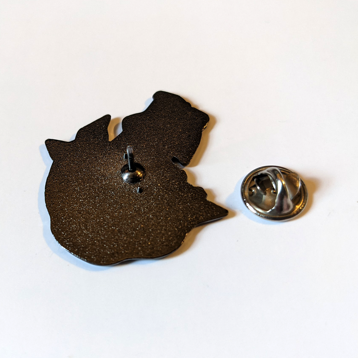 Photo. The back of a pin badge, and the clasp that holds it.