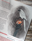 Photo. Interior from In The Red, with an illustration of an albino magpie standing on a glowing crystal.